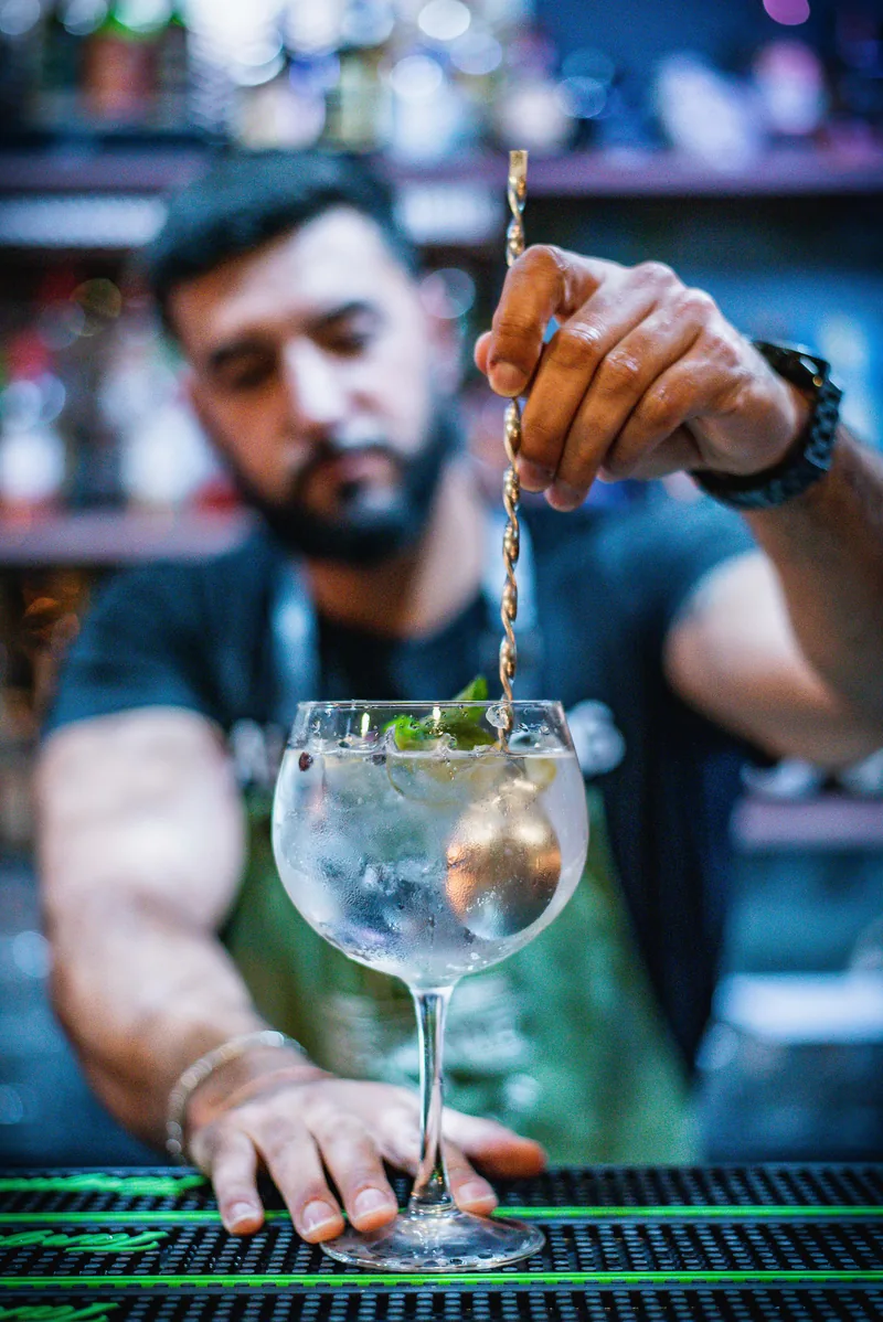 Bartender a preparar um gin no MENOSUM, Massamá
