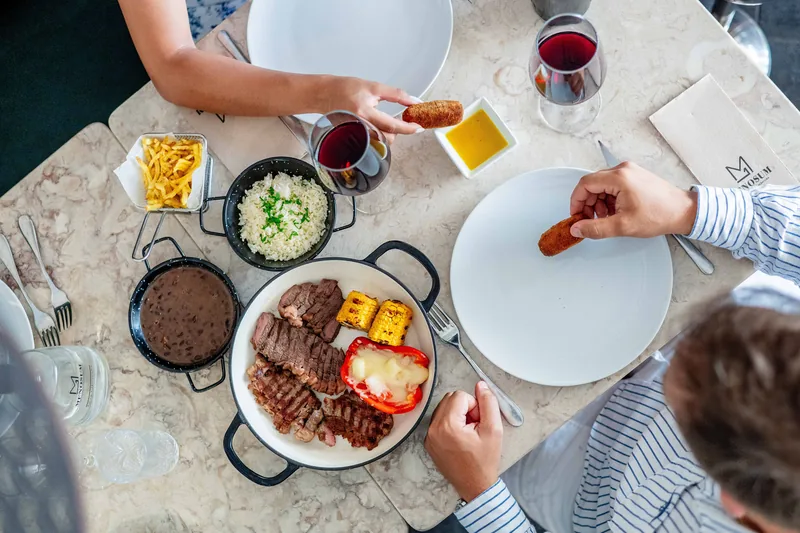 Mesa de partilha vista de cima com carnes confecionadas no MENOSUM, Massamá